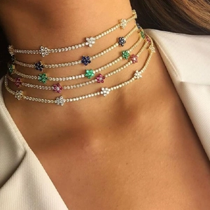 Close-up of stacked gold choker necklaces with colorful zircon flower pendants on a model