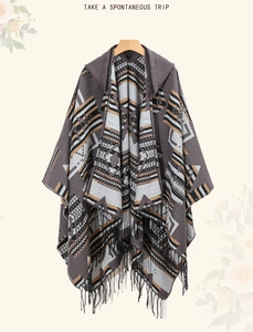Ethnic knit shawl with geometric patterns and tassels hanging on a wooden hanger