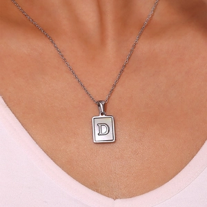 Detail of silver letter D rectangle pendant necklace with mother of pearl inlay on neck