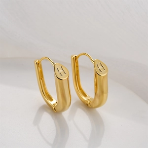 Polished 14K gold U-shaped earrings with letter H engraving on a minimalist background