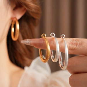 Detailed view of gold and silver matte geometric hoop earrings on a model's ear