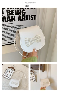 Detail view of mini off-white crossbody bag featuring a delicate pearl bow design