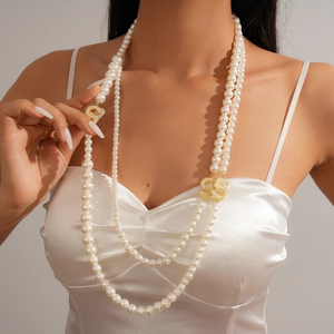 Close-up of elegant multi-layer pearl necklace with a sparkling crystal number 5 charm