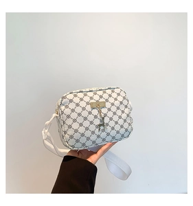 Close-up of white monogram pattern leather crossbody bag with gold deer charm detail
