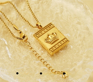 Detail of gold rectangular stainless steel pendant with crown and moon star engraving