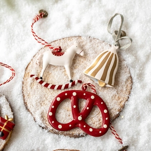 Hand-painted Christmas tree ornaments set with bell and rocking horse on snowy wood