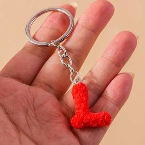 Detail of red letter L keychain with embossed rose pattern texture and silver ring