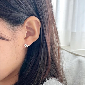 Close-up of minimalist sterling silver bean studs worn on ear with mirror finish