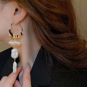 Close-up of vintage Baroque irregular pearl tassel earrings worn by a model in black outfit