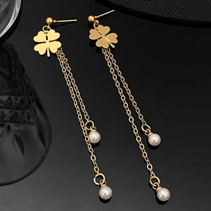 Detail of long gold tassel earrings with clover metal charm and white pearl drop