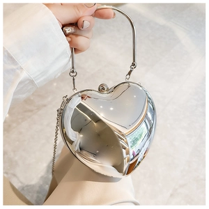 Silver mirror heart-shaped evening bag with metal handle and chain strap on marble floor