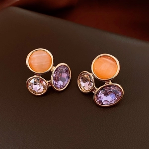 Detailed macro view of gold-tone triangle earrings with orange, pink, and purple crystals