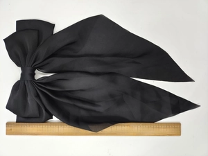 Detail view of large black satin bow hair clip with measurement scale showing 33cm length