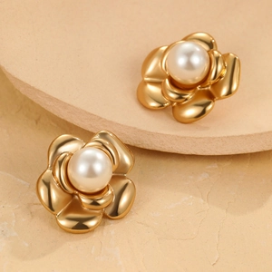 Detail of French style golden camellia earrings with white pearl centers on stone