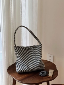 Dettaglio della trama in maglia di una borsa intrecciata nero bianca grigia con puntini