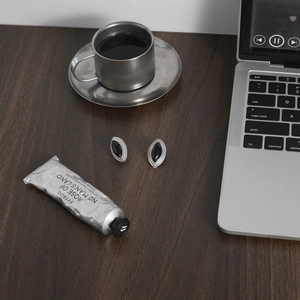 Detail of vintage black enamel stud earrings placed on a dark walnut wooden desk