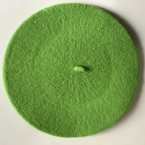 Detailed top view of grass green knit beret showing wool blend texture and top stem detail