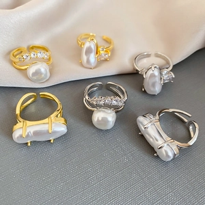 Detailed view of baroque pearl gold and silver rings with inlaid crystals on satin