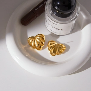 Chunky 18k gold plated heart stud earrings with pleated texture in a lifestyle setting