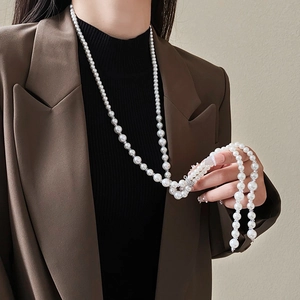 Elegant long pearl necklace with crystal accents styled on a brown suit for women