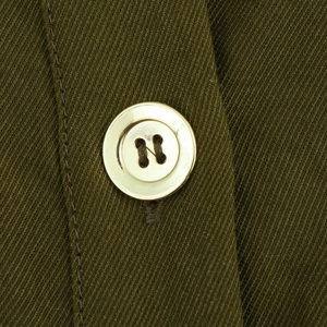 Detail of a polished gold button on high-quality army green twill fabric dress