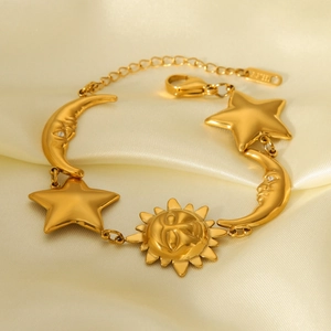 Detail of 18K gold celestial sun moon star charms on a polished stainless steel chain