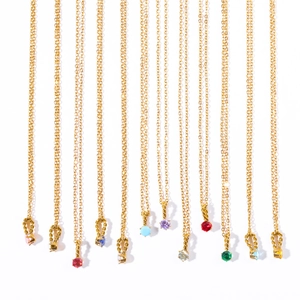 Close-up of golden necklaces with colorful birthstone pendants and spiral link details