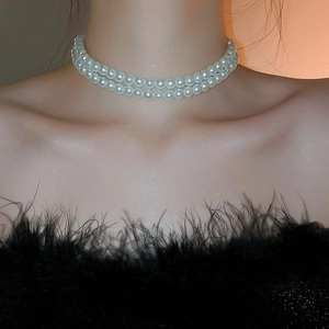 Gros plan d'un élégant collier ras-du-cou à double rang de perles blanches avec lumière chaude