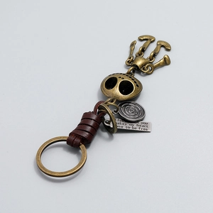 Porte-clés crâne en bronze vintage avec lanière en cuir tressé et plaque gravée
