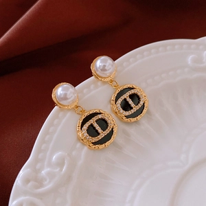 Detail of gold-plated pig nose earrings with pearls and zircon on a ceramic dish