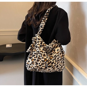 Close-up of leopard print quilted tote bag with wide strap on woman in black blazer