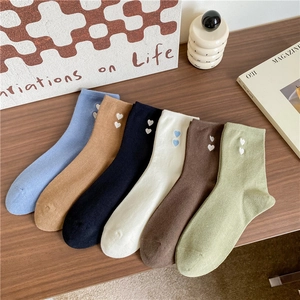 Detail of six pairs of cotton socks with embroidered double hearts on a wooden table