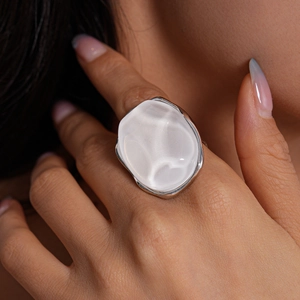 Close-up of geometric resin earring with pearlescent white stone and irregular silver base