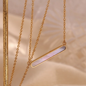 Détail d'un pendentif rectangulaire en nacre plaqué or 18K sur une fine chaîne dorée