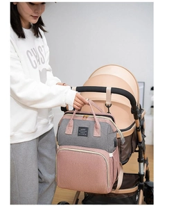 Pink and grey diaper bag hanging on a stroller hook with KONO logo details