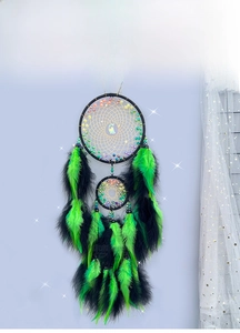 Detail of black and neon green feathers on a handmade dreamcatcher with cat pendant