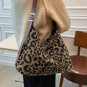 Chic leopard print canvas tote bag with brown leather strap worn by a model in a cafe