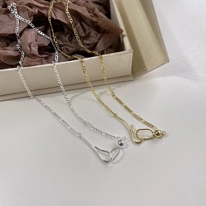 Detail of gold and silver Figaro chain necklaces with ball hook clasp in a gift box