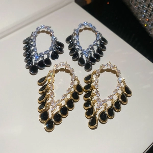 Detailed macro view of 18K gold plated teardrop earrings with luxury black pendants