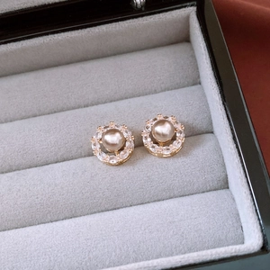 Macro shot of 14k gold plated pearl flower earrings featuring zircon halo in velvet box