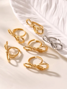 Macro shot of gold and silver bow-knot open rings on a white textured tray