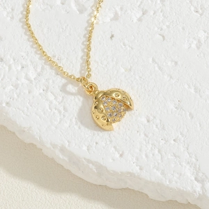 Macro detail of golden ladybug pendant necklace with shimmering white zircon stones
