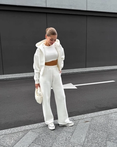 Détail d'un ensemble de sport blanc 3 pièces avec veste à capuche, haut court et pantalon