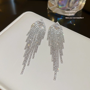 Macro shot of silver tassel earrings with sparkling rhinestones on a white tray