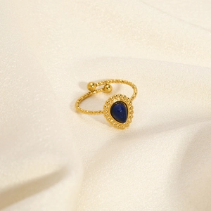 Macro shot of retro gold ring with pear-shaped blue stone on white silk background