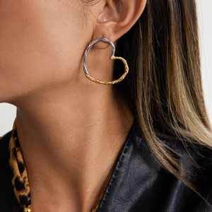 Detail of two-tone heart earrings with lava texture shown on model in black leather jacket