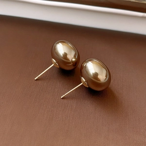 Detailed view of glossy dark brown oval earrings with silver needles on a textured surface