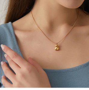 Detailed view of a golden 3D geometric teddy bear pendant necklace on a model