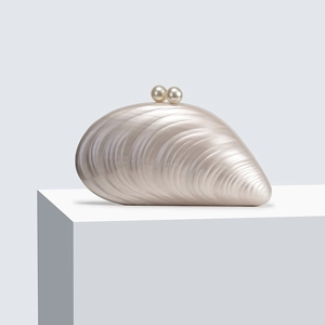Detailansicht einer weißen Abendtasche in Muschelform mit Perlenverschluss und Struktur