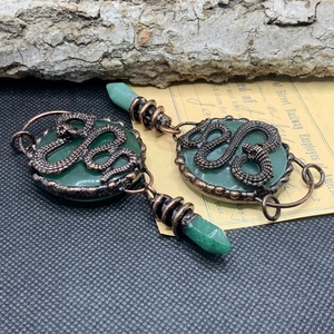 Detail of vintage bronze snake pendant with green quartz and hexagonal crystal